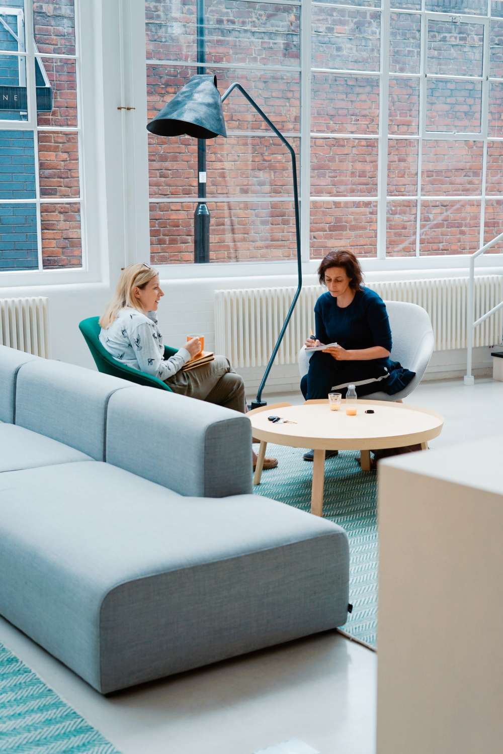 Två lönekonsulter som samtalar om löneadministration i loungemiljö på en professionell lönebyrå i Göteborg.